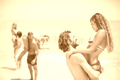 Smiling young man lifting woman at beach