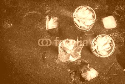 Alcohol cocktail made from golden tequila with ice cubes and mint. On a black concrete table. Copy space top view
