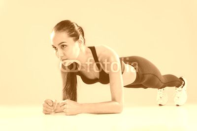 Focused beautiful young sportswoman working out and doing plank
