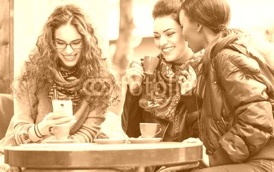 Women in cafe showing pictures on smart phone