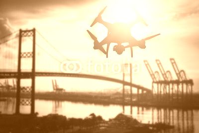 Silhouette of Unmanned Aircraft System (UAV) Quadcopter Drone In The Air Over Shipping Port.