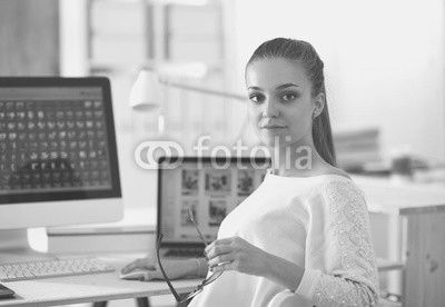 Young woman working in office, sitting at desk