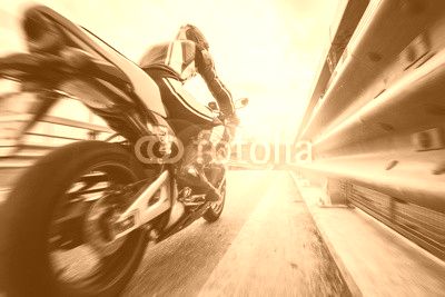 Moto da strada sfreccia vicino al guard rail al tramonto