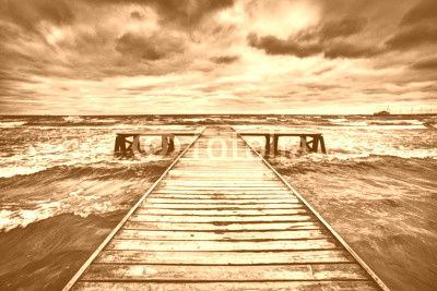 Old wooden jetty during storm on the sea. Dramatic sky