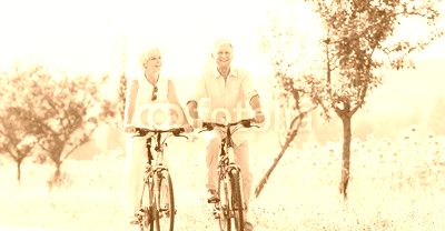 Senioren, Paar aus Frau und Mann, fährt Fahrrad an einem Sonnenblumen Feld