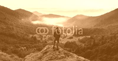 Man standing on top of cliff at sunset