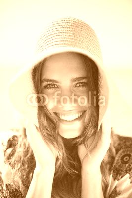 Portrait of happy young woman wearing hat at beach