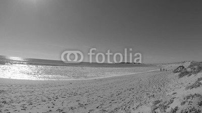Unrecognizable people on the beach, with the Trafalgar lighthouse in the background, on the coast of Cadiz, Spain