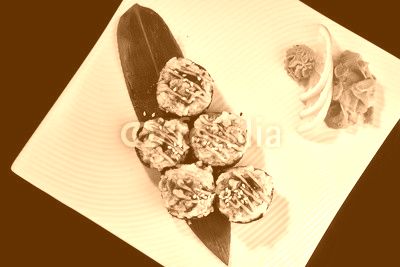 Baked Sushi Roll with crab, eel fish and spicy salmon served with vasabi, pickled ginger and lemon slice on white plate on black background