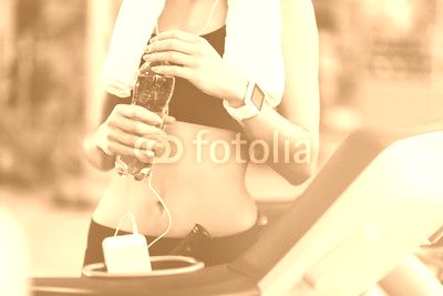Slim woman holding a bottle after workout