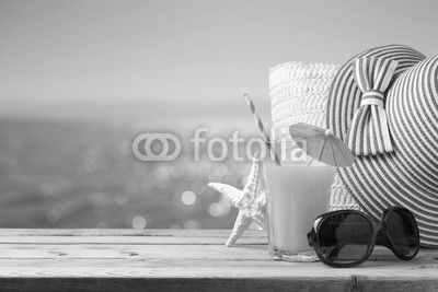 Summer holiday vacation concept with orange juice, hat and sunglasses over sea beach background