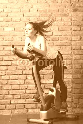 Active woman using exercise bike at the gym.