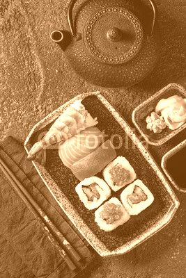 Sushi Set nigiri and sushi rolls in dark ceramic plate with soy sauce, iron teapot and chopsticks over black stone texture background. Top view with space. Japan menu