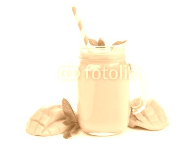 Mango coconut smoothie in a mason jar glass with mint and straw isolated on white
