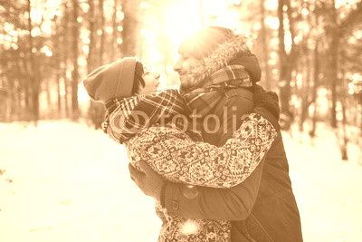 Young hipster couple hugging each other in winter forest