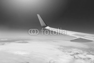 wing of an airplane flying high in the sky above the clouds