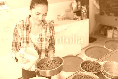 pretty woman preparing bowls of dog food at animal shelter