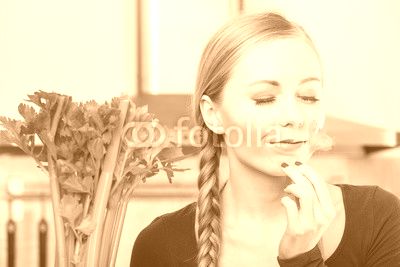 Woman in kitchen holds green celery