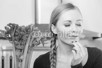 Woman in kitchen holds green celery