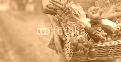 Portrait of a happy young farmer holding fresh vegetables in a basket. On a background of nature The concept of biological, bio products, bio ecology, grown by own hands, vegetarians, salads healthy
