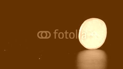 rolling orange fruit slice on black background, slow motion
