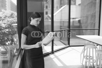 Young white businesswoman reading document in modern office
