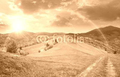 fence on hillside meadow in mountain at sunset